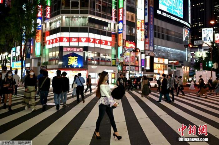 当地时间5月25日，人们穿过东京新宿区的一条街道。