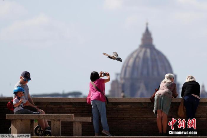 曾经一度成为全球新冠肺炎疫情最严重的国家的意大利终于迎来了一些生活的喧嚣，当地时间5月12日，意大利罗马，人们从露台上眺望景色，拍摄圣彼得大教堂雄伟的穹顶。